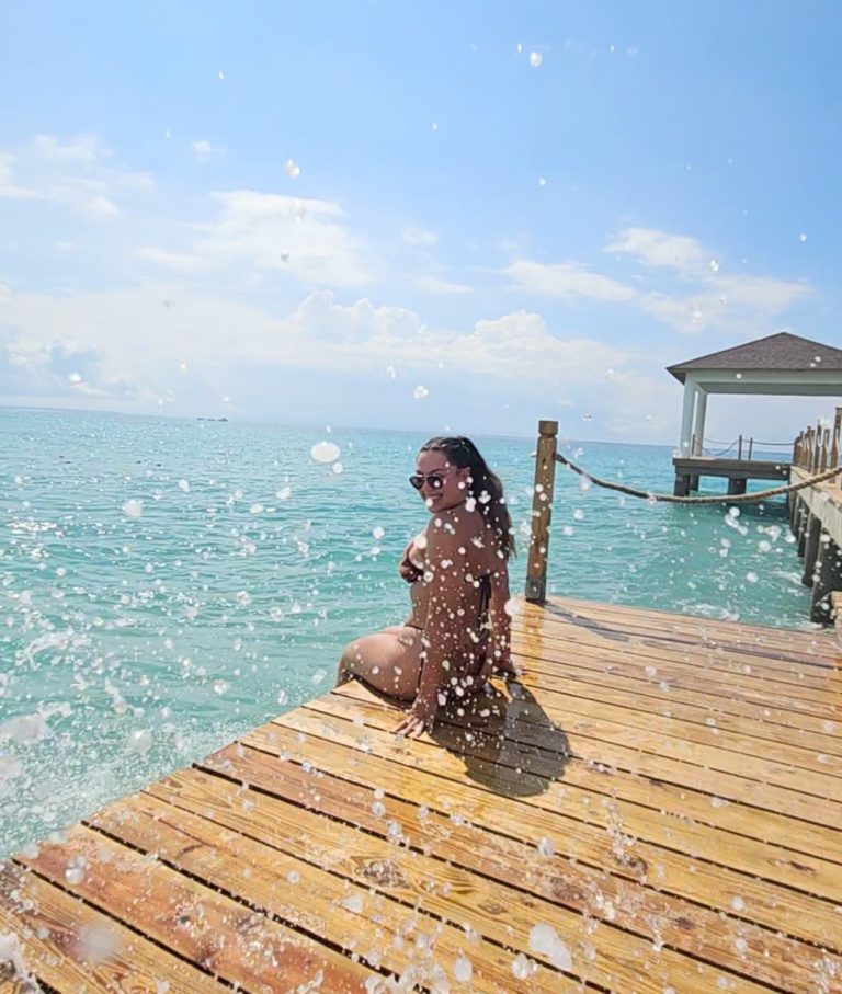 Charlotte, travel planner, sitting on a wooden pier, water splashing around on a sunny day in the Dominican Republic